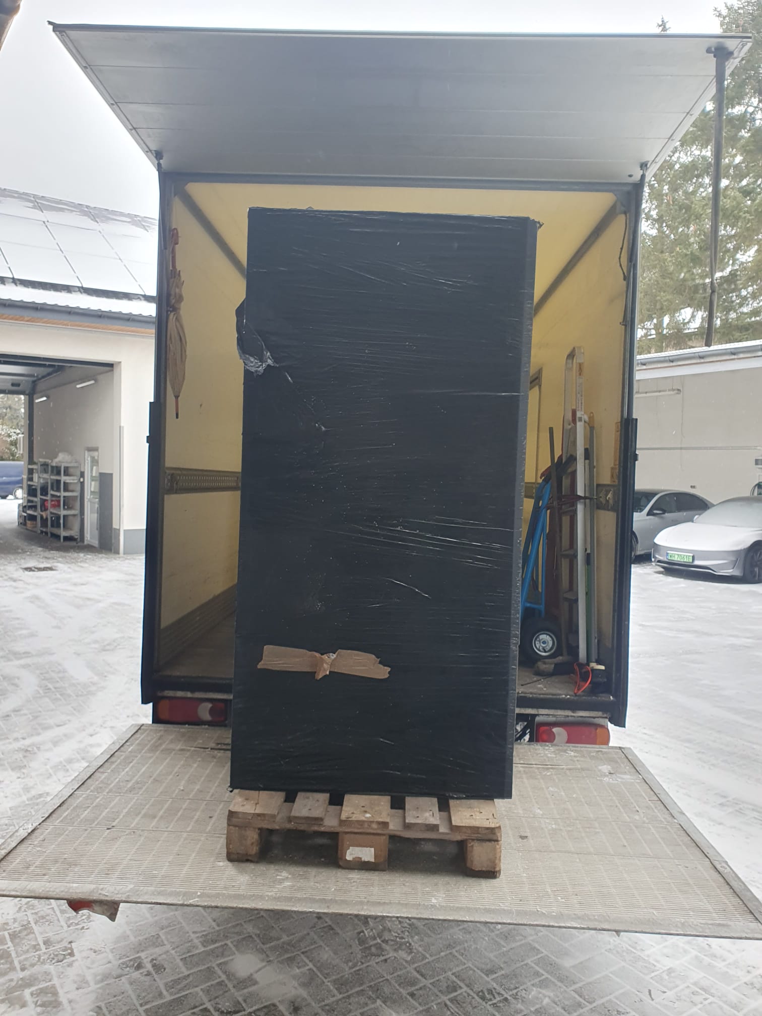Zafoliowany mebel na palecie na windzie załadunkowej samochodu